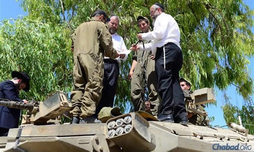 Swerdlov, left, and Prus aboard tanks to assist soldiers wrapping tefillin. (Photo: Meir Alfasi)
