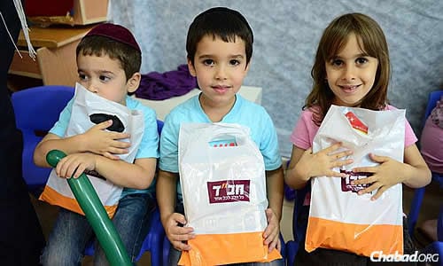 Children in Sderot, close to the Gazan border and showered by rocket attacks, clutch activity bags handed out by representatives of the Chabad Victims Terror Project. (Photo: Meir Alfasi)