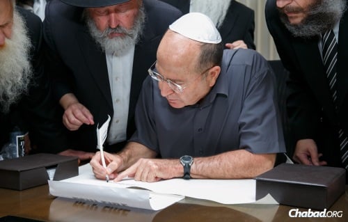 Defense Minister Moshe Ya'alon pens the first letter of a Torah scroll written for the security of the troops. To his left is the sofer, Rabbi Mordechai Lishner; on his right is Rabbi Yosef Yitzchak Aharonov, director of the Chabad Youth Organization in Israel. (Photo: Shalom Lavi)