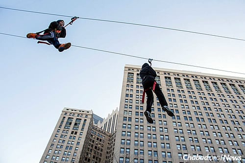 Kids and other attendees of the downtown Chanukah event last Sunday ride on the 300-foot zip line.