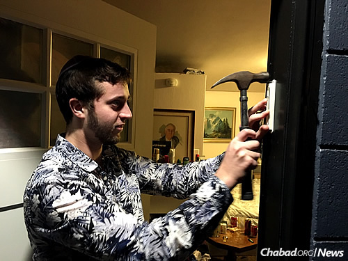 Jacob Valleau affixes a mezuzah to his doorpost, part of the mezuzah-loan program for students put into place by Rabbi Berel and Rivkah (Rivky) Gurevitch, co-directors of Chabad of Eugene in Oregon.