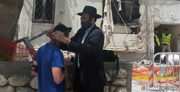 Rabbi Moshe Vilenkin assists a local resident with tefillin.