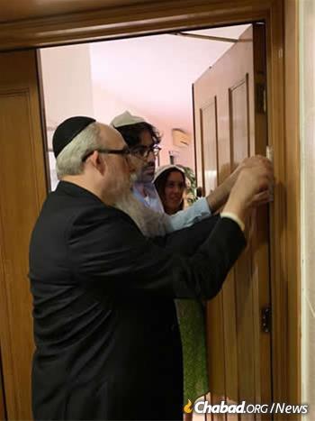 Rabbi Mordechai Avtzon, founder and co-director with his wife, Goldie, of Chabad of Hong Kong, helps residents affix a mezuzah to their door.