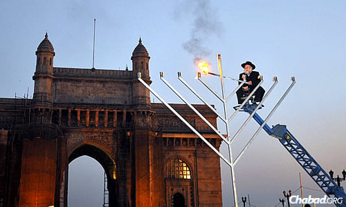 Rabbi Shimon Rosenberg of Afula, Israel, the father of Rivkah Holtzberg, lights a 25-foot steel menorah during Chanukah 2008 in front of the Gateway of India in Mumbai just weeks after his daughter and son-in-law, Rabbi Gavriel Holtzberg, were killed in a terrorist attack. Gavriel Holtzberg would light that menorah each year. (Photo by Serge Attal/Flash90)
