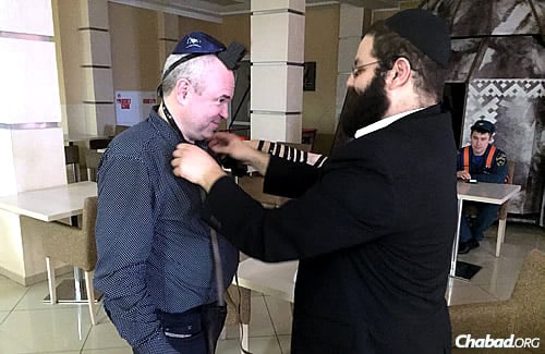 The rabbi helps Russian Deaf historian Victor Palenny put on tefillin.